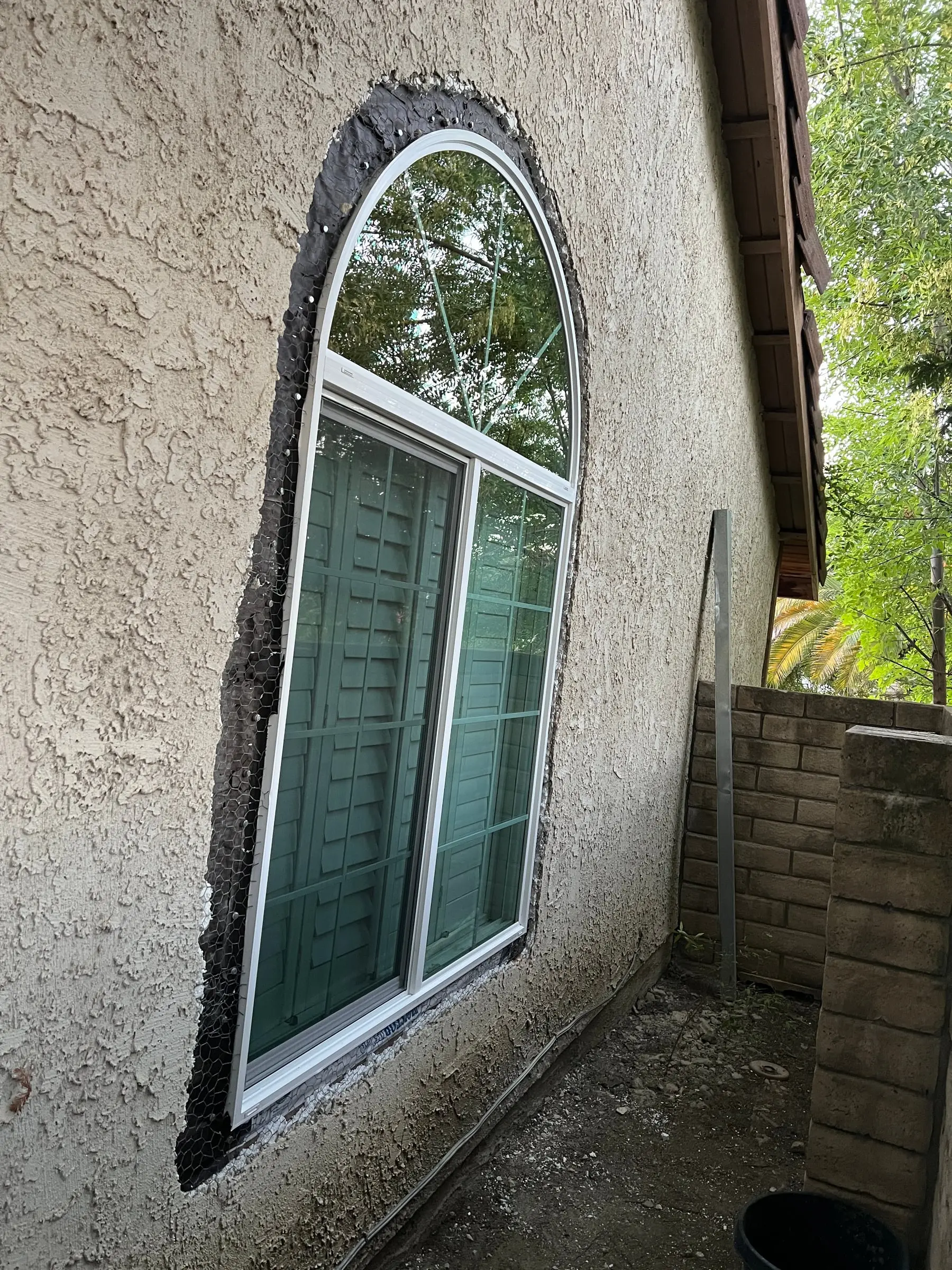 New white arched retrofit window installed in a stucco home