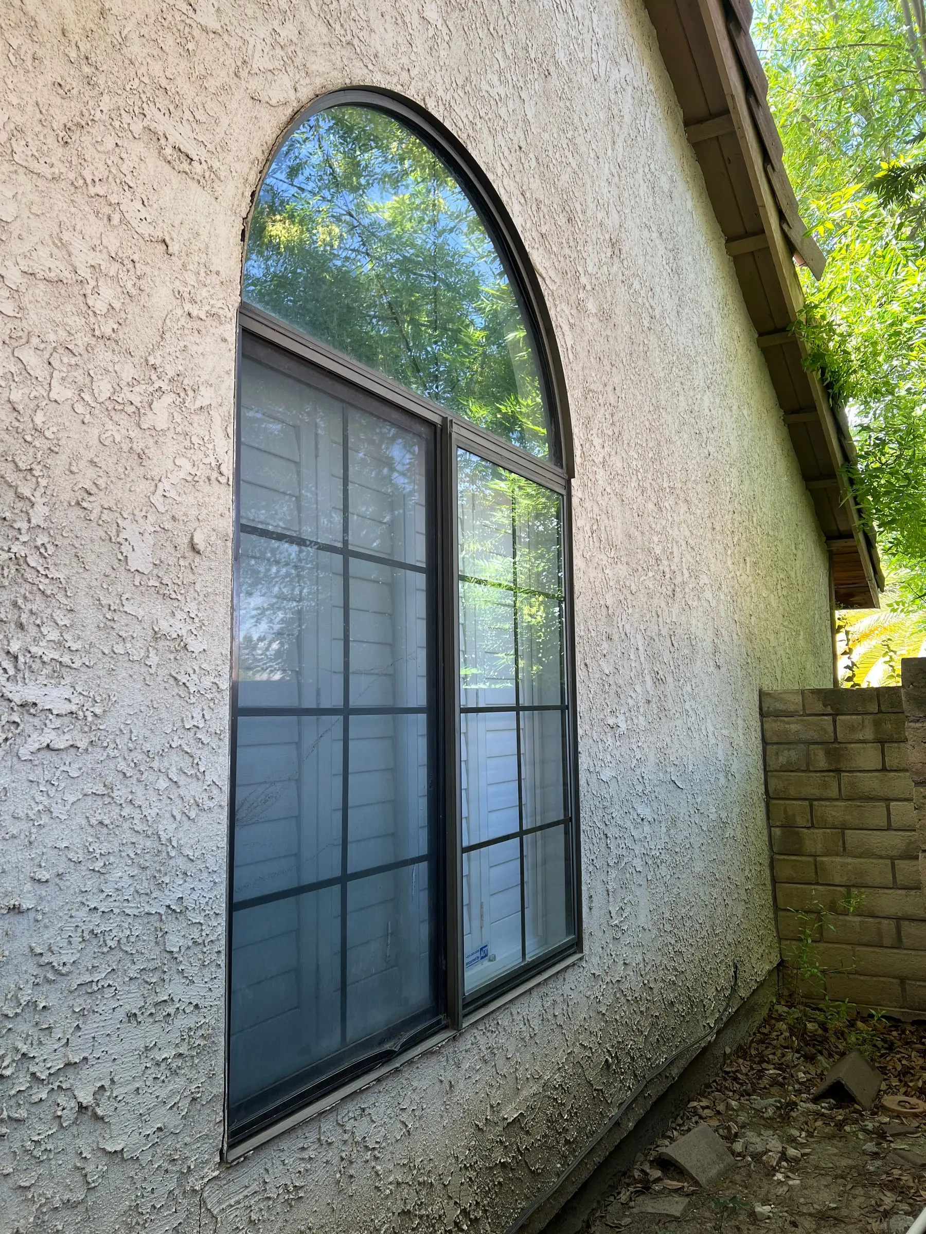 Arched window with an older dark frame before replacement