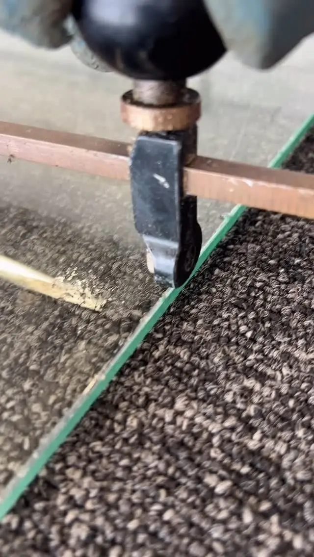 Close-up of a glass cutter scoring a sheet of glass