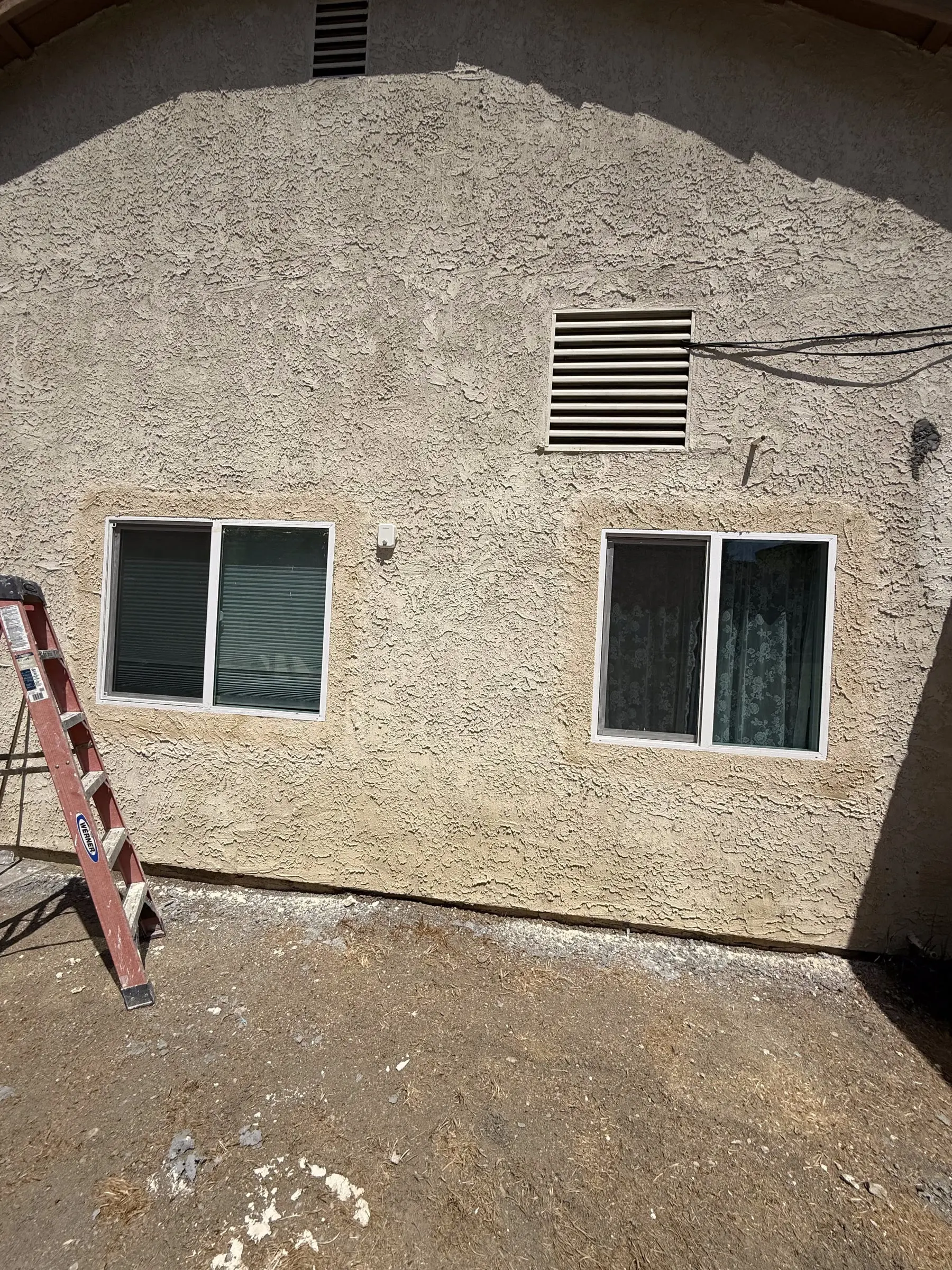 Retrofit window installation in progress with a ladder against a stucco wall